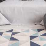 Contemporary abstract rug with geometric design at foot of bed