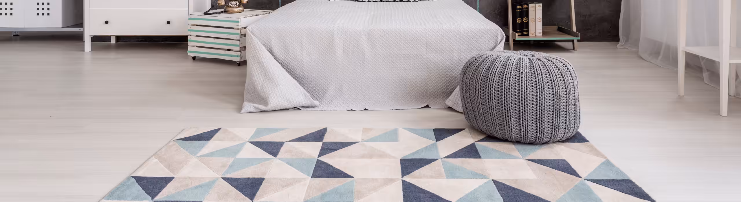 Contemporary abstract rug with geometric design at foot of bed