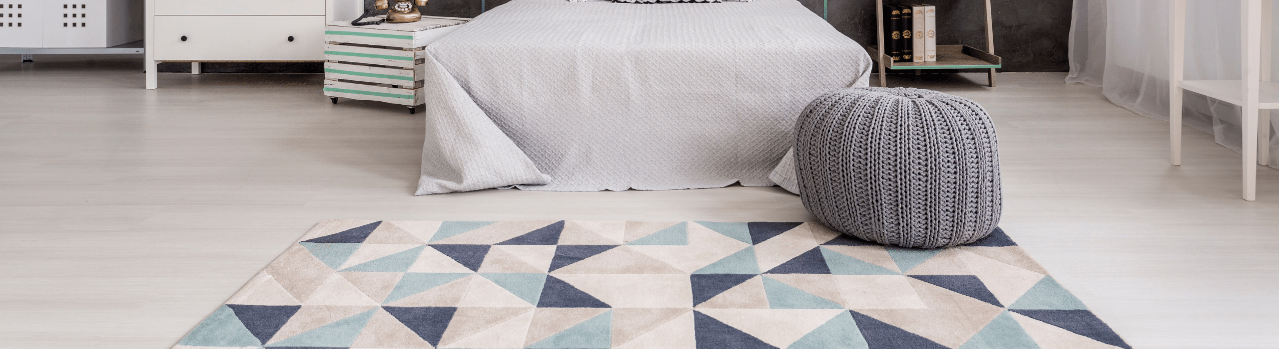 Contemporary abstract rug with geometric design at foot of bed