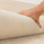 Person rolling out carpet during DIY carpet installation