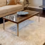 Living room with couch, chair, fireplace, and light colored rug on dark wood floor