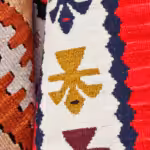 Detail of hanging collection of kilim rugs, featuring several colors and designs