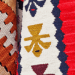 Detail of hanging collection of kilim rugs, featuring several colors and designs