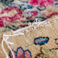 Closeup of raveling on an Oriental rug in need of repair