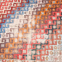 Colorful rug with geometric patter showing pile wear in need of repair