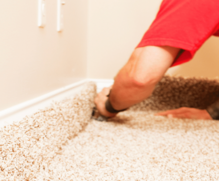 Professional carpet installation being done in home with beige carpet