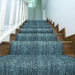Blue carpet stair runner going up brown wooden stairs