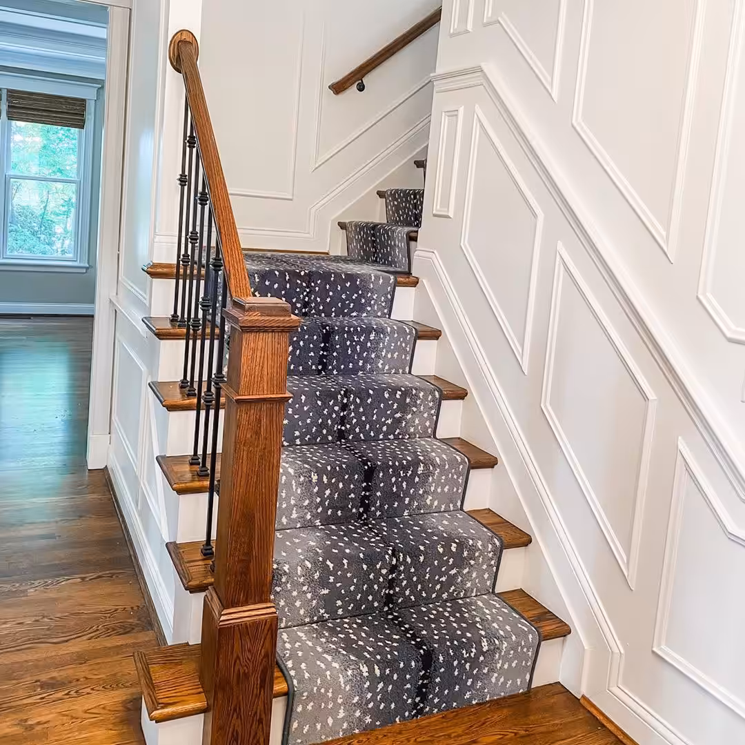 Blue and gray stair runner with white spots going up brown and white wood staircase