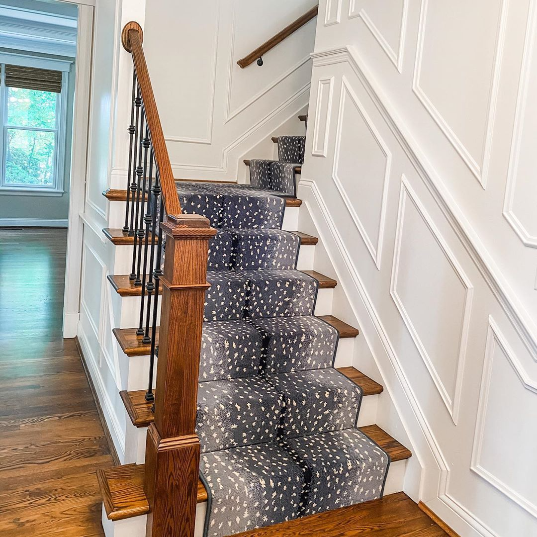 Blue and gray stair runner with white spots going up brown and white wood staircase