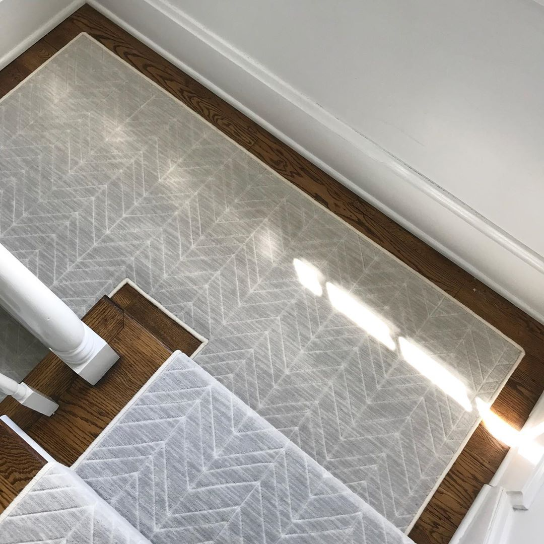 Stair runner on brown wooden steps with gray and white geometric pattern