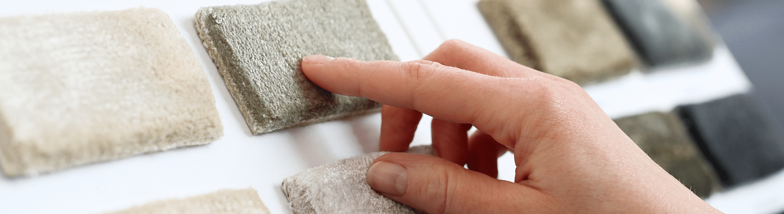Closeup of hand touching different types of carpet samples