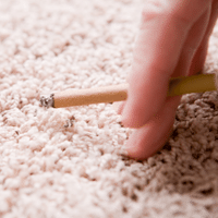 Fingers holding cigarette next to rug causing odors