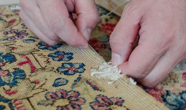 Closeup of person repairing a hole in an Oriental rug