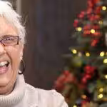 A Rug Gallery employee smiling with a Christmas tree behind them
