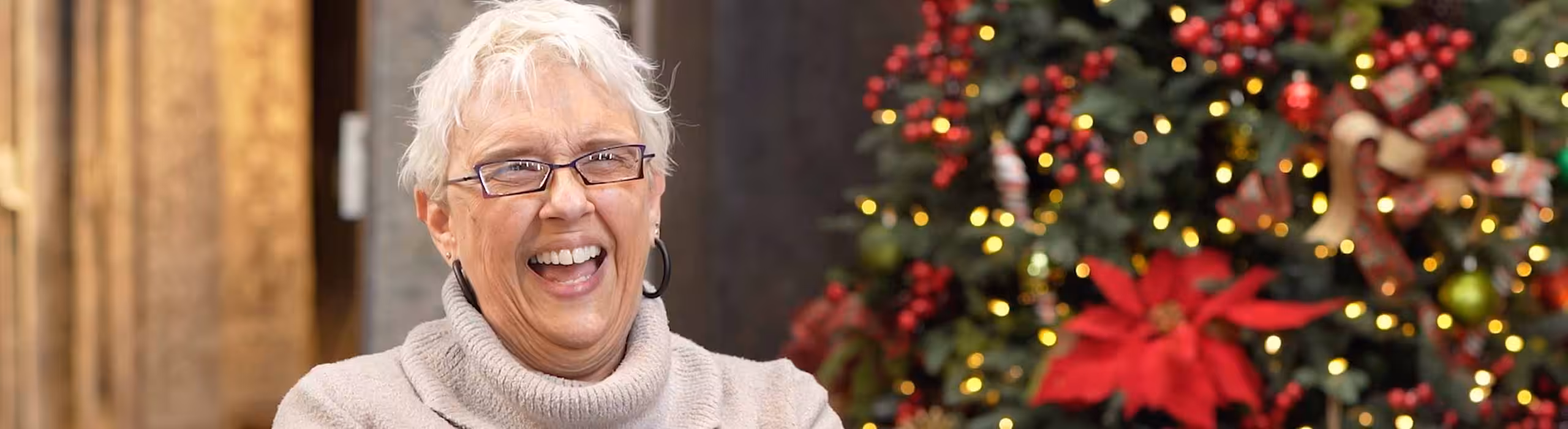 A Rug Gallery employee smiling with a Christmas tree behind them